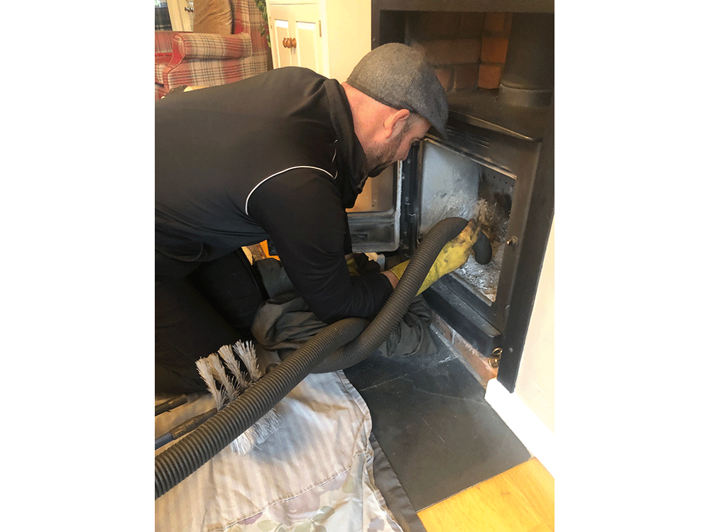 Chimney sweep cleaning wood burner with vacuum cleaner