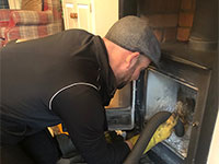 Chimney sweep cleaning wood burner with vacuum cleaner